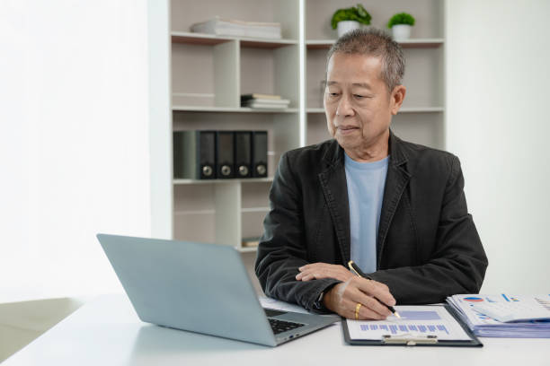 istock Asian senior businessman working at office with documents on table Planning to analyze financial reports business plan investment financial analysis concepts Use a calculator 2043132691