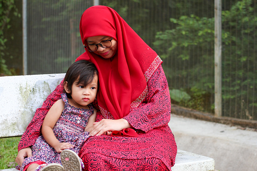 A Muslim woman is spending quality time with her young daughter at the park