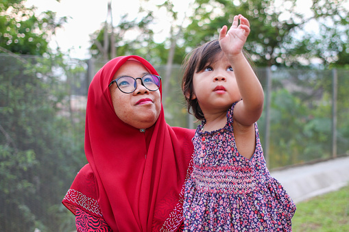 A Muslim woman is spending quality time with her young daughter at the park