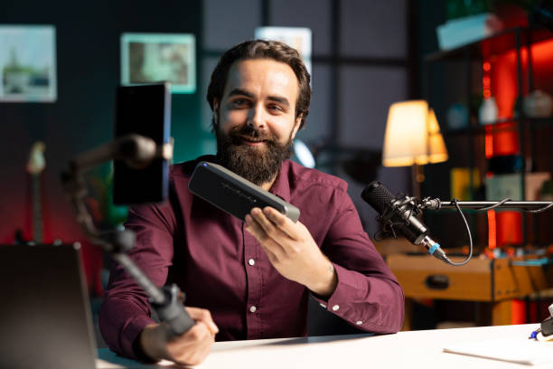 istock Influencer delighted by high end music playing device, filming with smartphone on selfie stick 2043189127