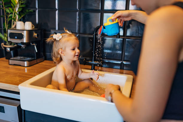 istock An unrecognizable young mother is playing with her daughter sitting in the kitchen sink 2043191224
