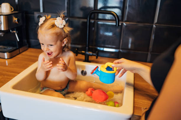 istock An unrecognizable mother is playing with her daughter sitting in the kitchen sink 2043191743
