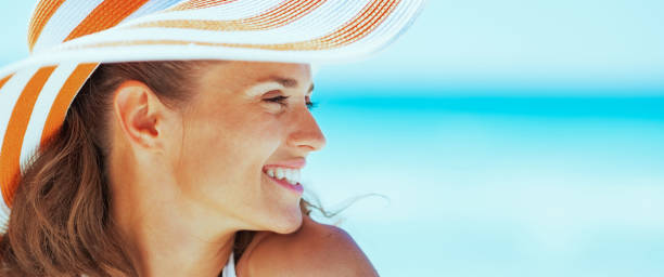 istock Woman in swimsuit and beach hat looking on copy space 2043199050