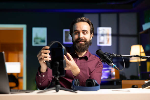 istock Man promoting headphones, doing influencer marketing using smartphone on tripod 2043200621