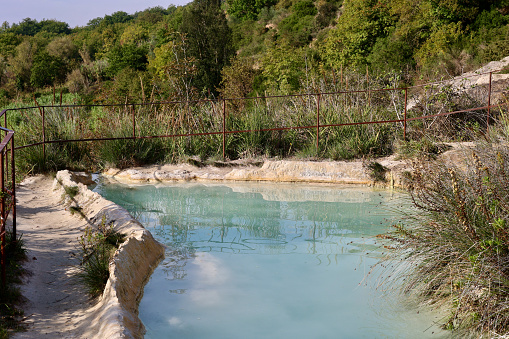 Thermally heated, natural swimming hole with milky-blue water and cascades running down the cliffside. The hot spring.