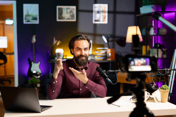 istock Influencer in neon lit home studio filming smart light bulb review for online streaming platforms 2043214014