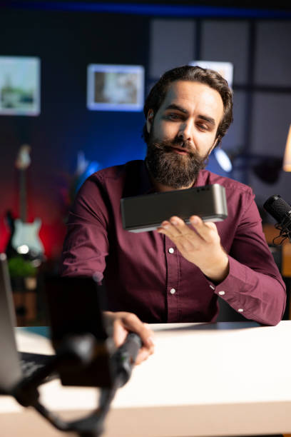 istock Influencer showcasing music playing device, capturing footage with cellphone camera 2043217134