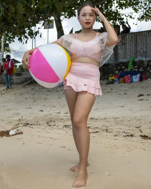 A Filipino girl playing with a beachball on a sandy beach