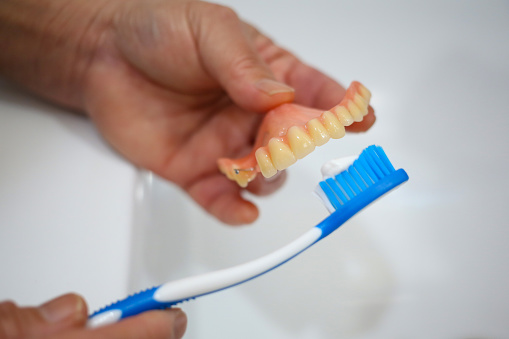 A hand brushing teeth denture