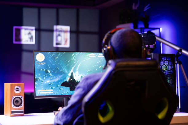 istock Man wearing headphones playing SF space videogame on PC screen 2043230493
