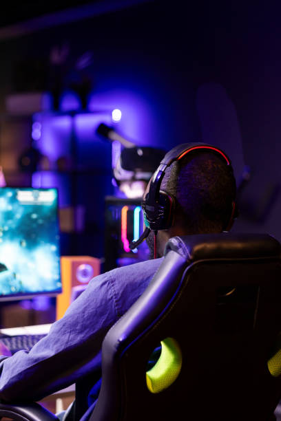 istock Gamer using headphones to discuss with mates while playing online SF videogame 2043231009
