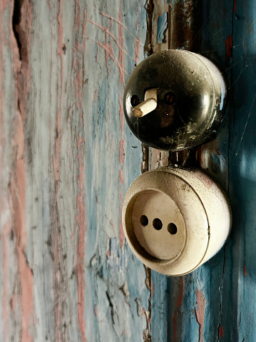 Old and weathered electric light switch and electrical outlet on wall with copy space