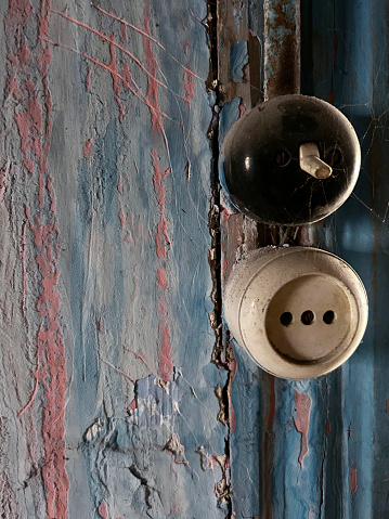 Old and weathered electric light switch and electrical outlet on wall with copy space