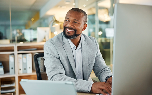 Business, thinking and happy black man on computer for inspiration, decision making or planning future in office at night. Vision, dream and professional with idea, problem solving or typing solution