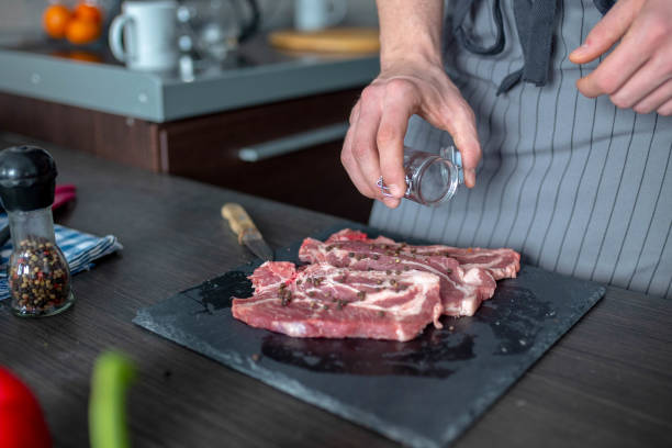le chef prépare la viande de veau crue. avant la cuisson, le chef ajoute du sel à la viande. - veal calf meat baking photos et images de collection