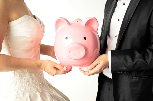 Bride and groom are holding a piggy bank.