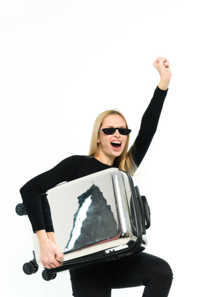 Pretty young woman with suitcase under her arm on white background. Girl in black clothes.