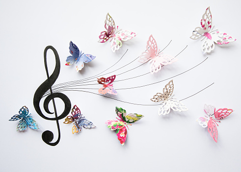 Colourful paper butterflies eminating from a musical stave.