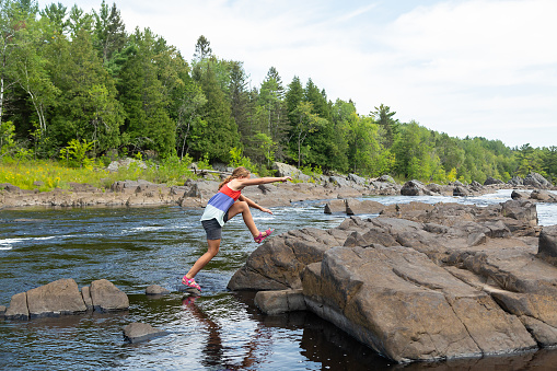 Young girl exploring the riverbank of the St. Louis River in Minnesota, USA. Taken at the Jay Cooke State Park on a beautiful summer day.