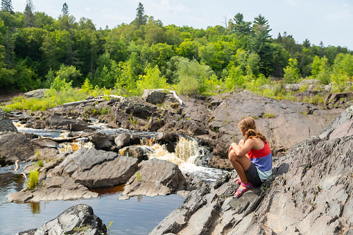 Young girl exploring the riverbank of the St. Louis River in Minnesota, USA. Taken at the Jay Cooke State Park on a beautiful summer day.