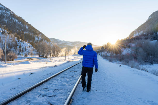 Mature man walks along train track in winter