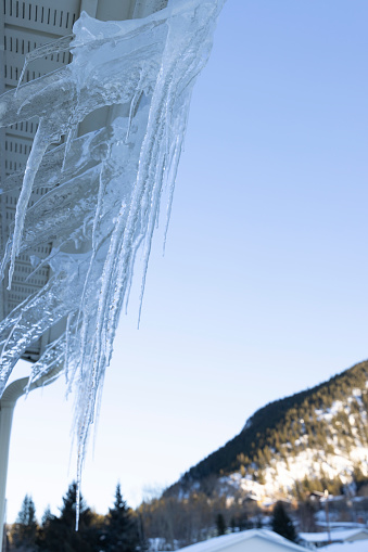 Detail of icicles hanging from home, mountains distant