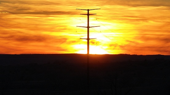 Sunset behind power pole at dusk