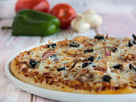 Chicken Tikka Pizza topping with capsicum, mushroom, tomato and olives served in dish isolated on table side view of arabic fastfood