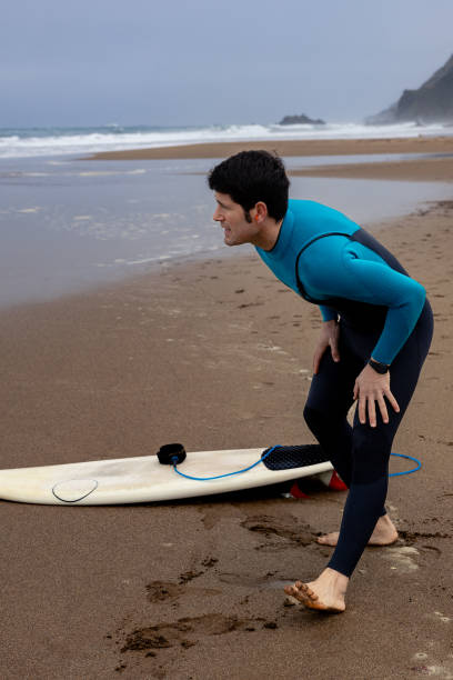 istock Young surfer smiling as he warms up before catching the waves, vertical photo. 2043385107