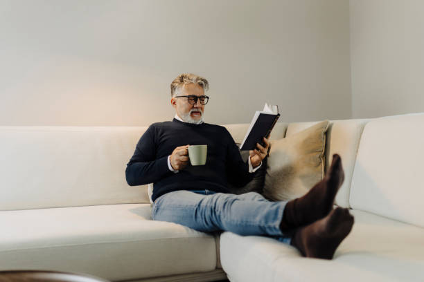 istock Senior man reading book and resting at home 2043387707