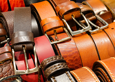 Leather belts handcrafted by artisans with metal buckles are available for purchase at the leather goods store