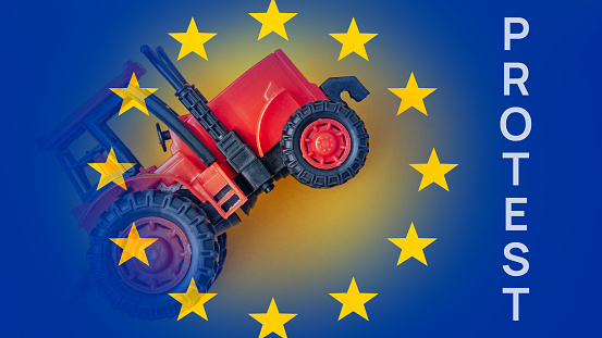 Tractor on background of flag of European Union and inscription protest, concept of farmers being abandoned, Tractor and flag of European Union. Farmers' protests, Farmers' crisis in European Union.