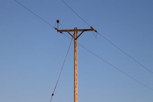 Telegraph pole in a field with blue sky