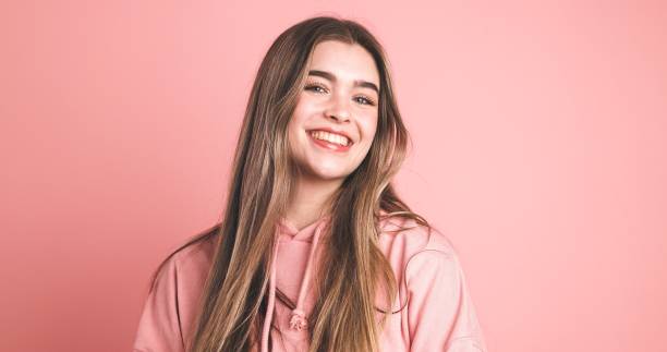 istock Smiling young woman on peach background looking at camera in studio 2043448904