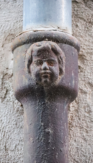 Face on old forged metal gutter in Alcoy city, Alicante. Modernist style