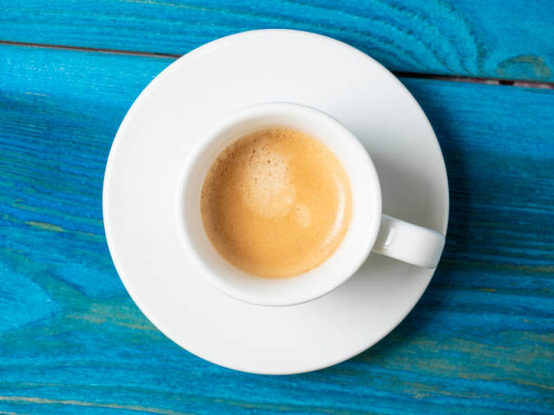istock white cup with freshly brewed espresso on a blue wooden background. Top view, flat lay, brown foam. Coffee concept 2043461584