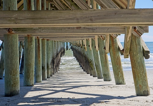 Beach and pier trusswork meet the Atlantic ocean at the 2nd street pier Myrtle Beach South Carolina.