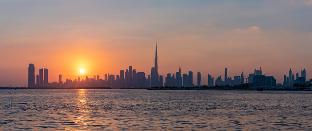 A panorama and colorful picture of Downtown Dubai at sunset, with the Burj Khalifa towering all high rises.