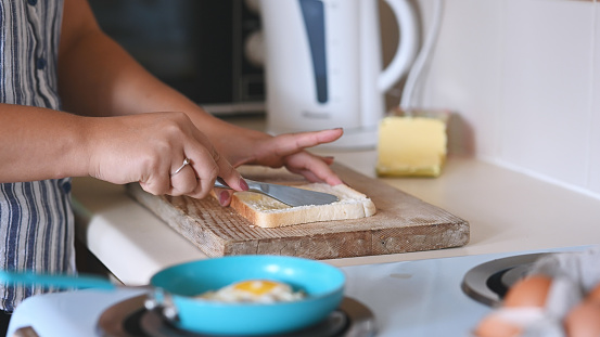 Hands, bread and sandwich in the kitchen with a hungry person making a snack or meal for lunch at home. Food, breakfast and homemade with an adult in their house, preparing a fresh appetizer