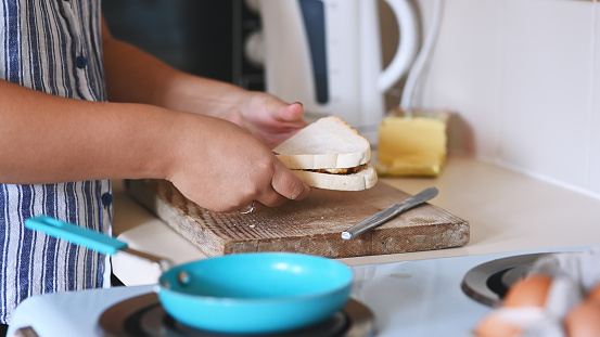 Hands, bread and sandwich in the home kitchen with a hungry person making a snack or meal for lunch. Food, breakfast and homemade with an adult in their house, preparing a fresh appetizer
