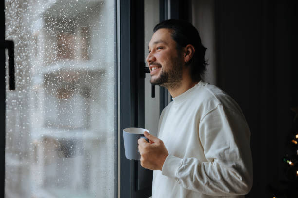 Man holding coffee cup while looking away at home