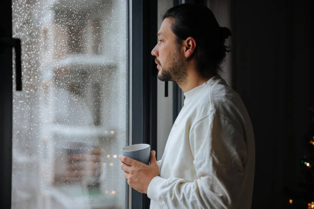 istock Man holding coffee cup while looking away at home 2043504642