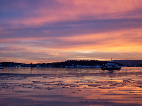 A beautiful sunset over the Oslofjord with a ferry approaching oslo