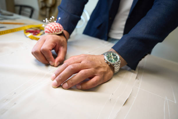 istock Clothier pinning pieces of fabric patterns along chalk lines 2043561813