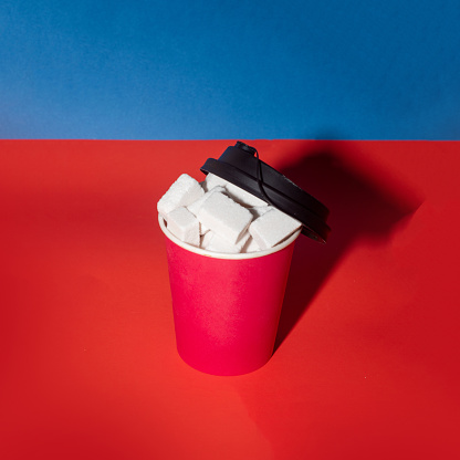 Disposable coffee cup and sugar cubes. Creative food concept. Copy space.