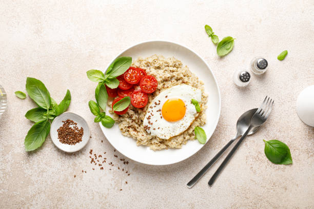 istock Oatmeal with fried sunny-side-up egg, tomatoes and basil, top view 2043604334