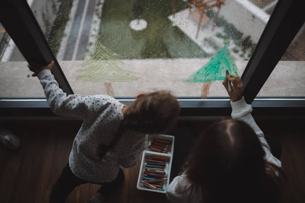 istock Young mother drawing with her little daughter on the window 2043617408
