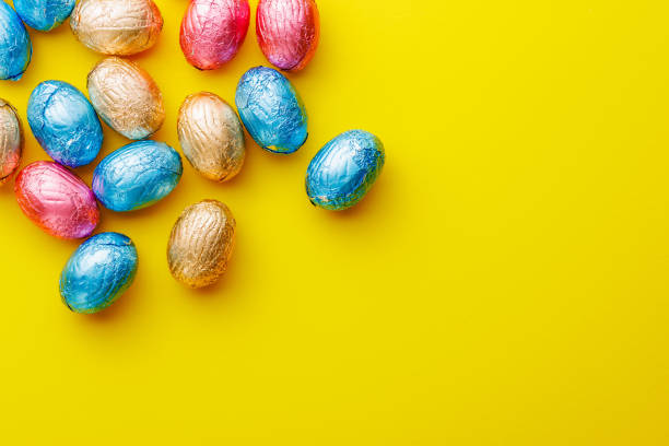 istock Easter chocolate eggs wrapped in aluminium foil on yellow background. 2043627774