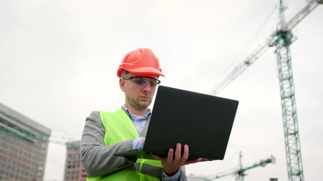 Man inspects territory of construction site outside, use gadget