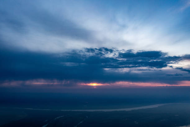 Immerse yourself in the captivating beauty of the heavens as day transitions into night with this stunning aerial photo capturing the sky at sunset. The warm hues and delicate clouds create a celestial canvas, offering a moment of tranquility and awe-inspiring beauty.